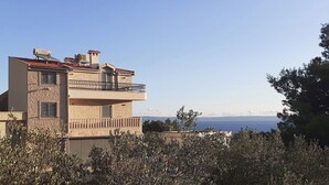A two-story building with a balcony, a view of the sea, and a clear sky.