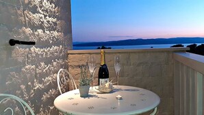 A balcony with a table set for two, a bottle of wine, and a candle.