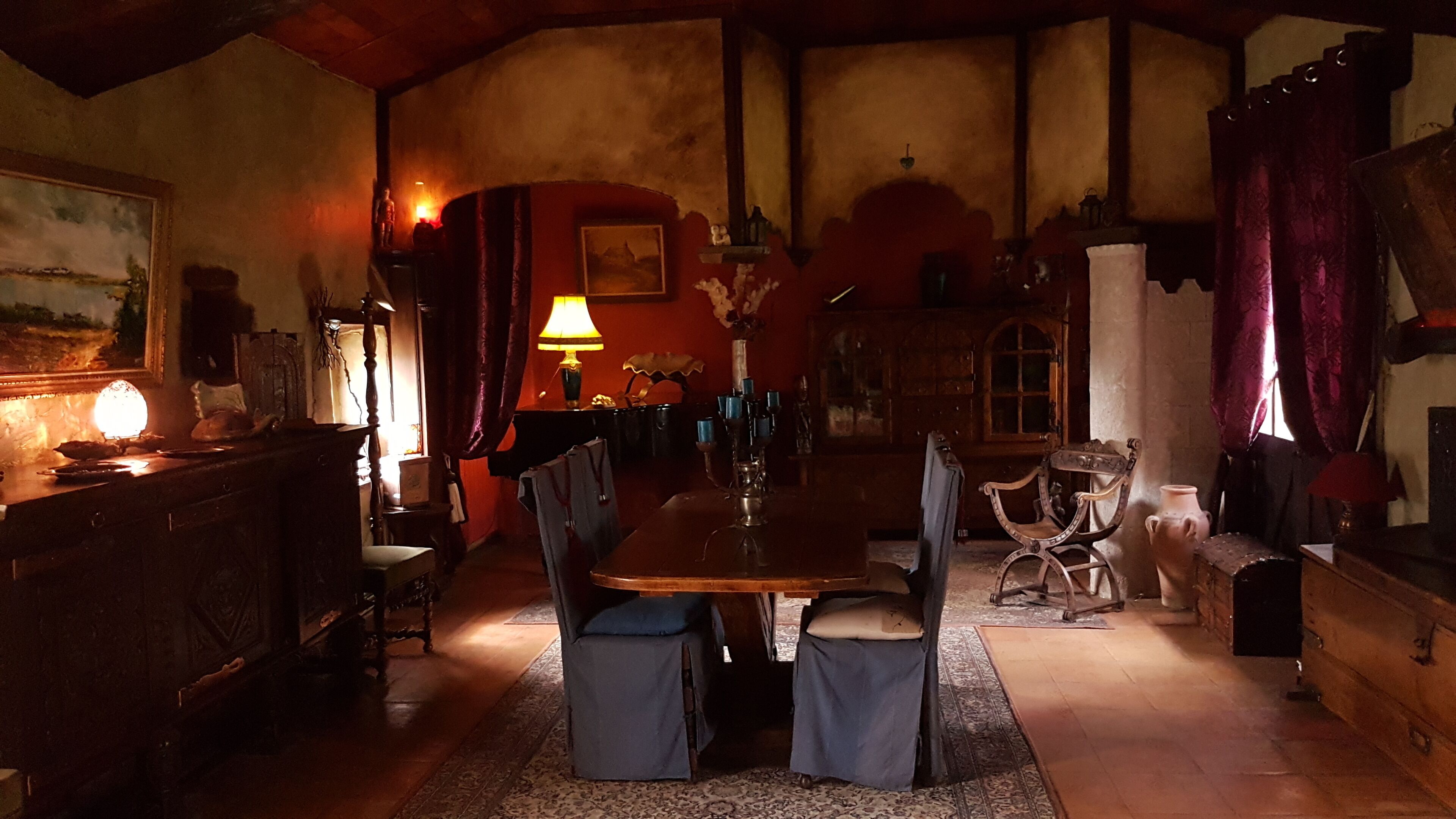 Ein schummriges Zimmer mit einem Holzespeise-tisch, Stühlen und einer Chandelier.