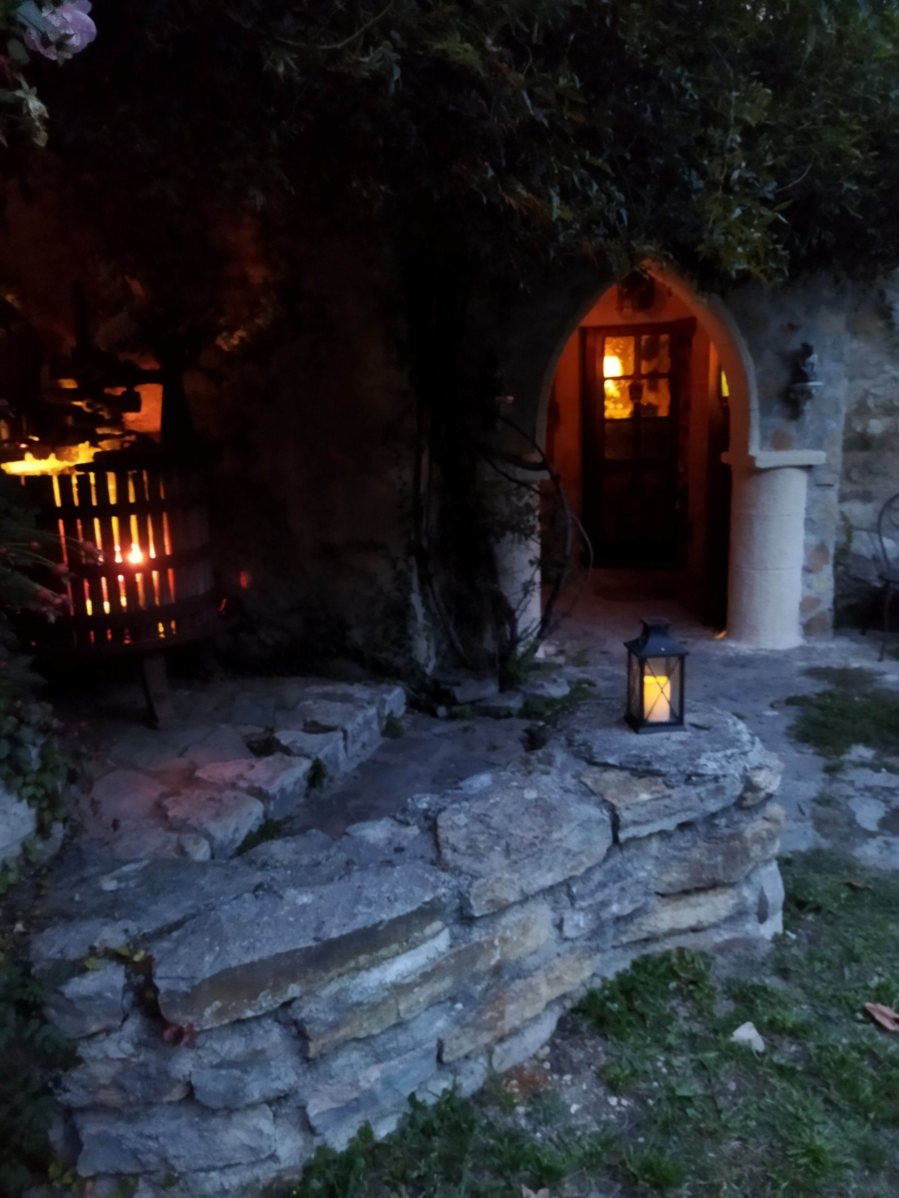 A stone pathway leading to a rustic building with a wooden door and a lantern.