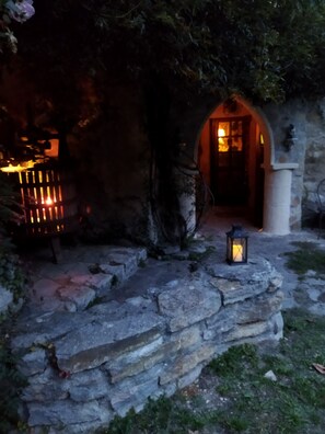 Un sendero de piedra que lleva a una construcción rústica con una puerta de madera y un farol.