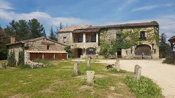 A stone building with a tiled roof, a wooden door, and a sign that reads "LA CROISE DES ARTS".