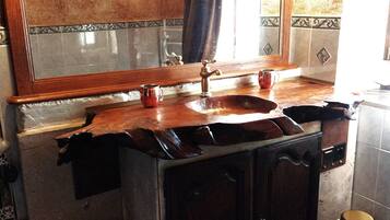 Un baño con tocador de madera, un lavabo y un espejo.