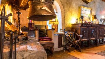 A rustic interior with a stone fireplace, wooden furniture, and a traditional lamp.