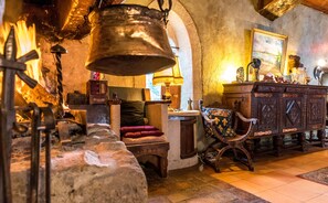 Un interior rústico con chimenea de piedra, muebles de madera y una lámpara tradicional.
