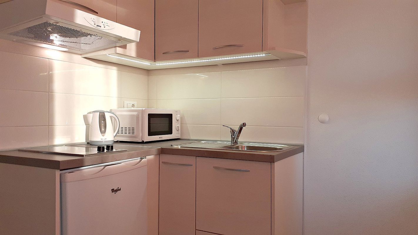 A compact kitchen with a microwave, kettle, and sink.