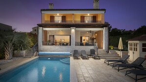 A two-story house with a swimming pool, outdoor seating, and a balcony. - Luxury villa with heated pool by the sea in a quiet area (Pula - Pomer)