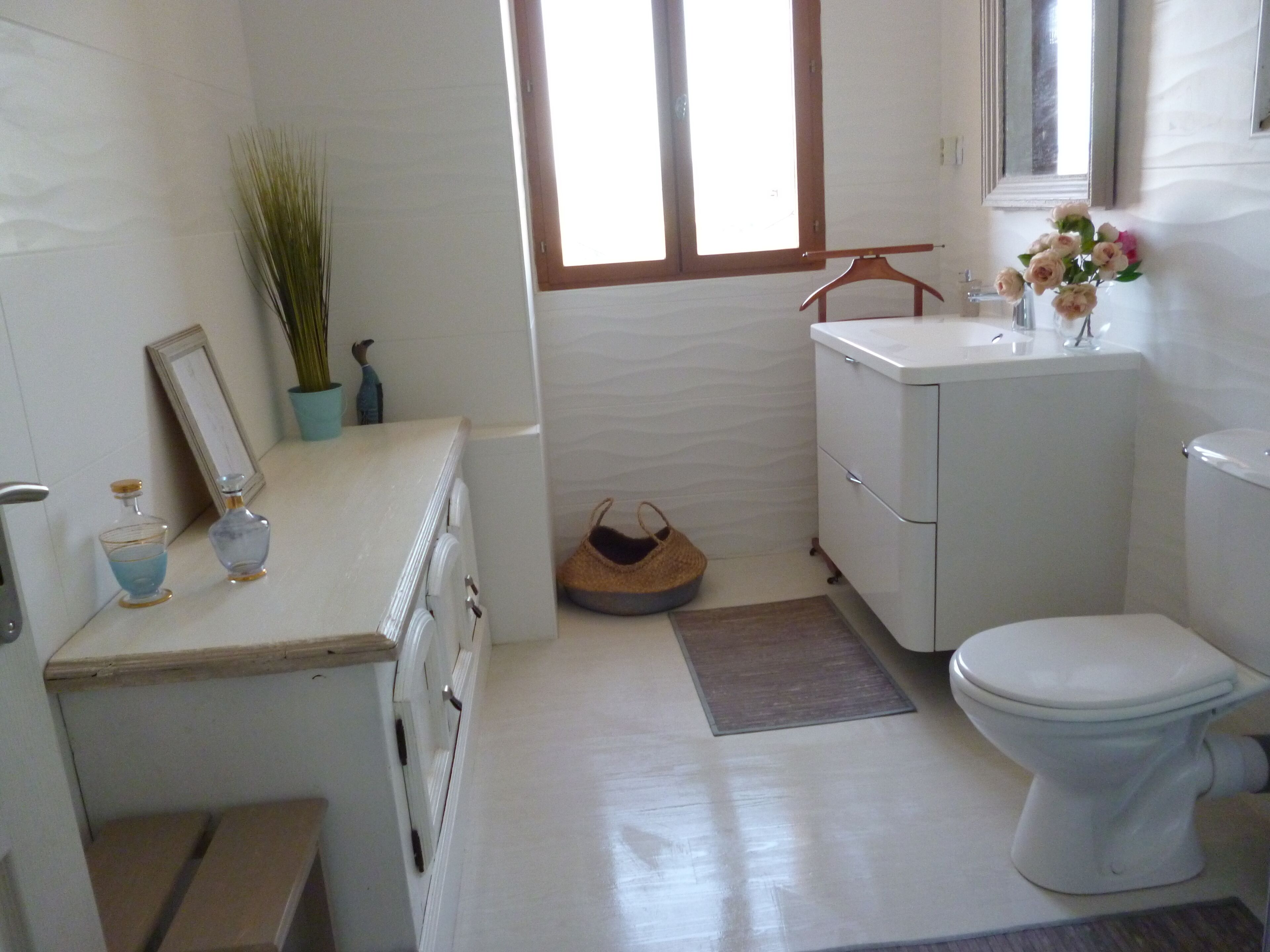 A bathroom with a toilet, a sink, a mirror, a window, and a small plant.