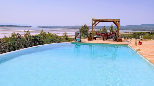 A clear blue pool with a wooden deck and a hammock.