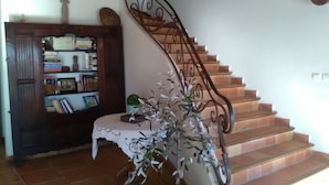 A staircase with a wrought iron railing, a wooden bookcase, and a small table with a plant.