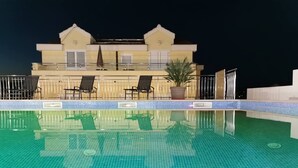 Una piscina con solárium y sillones de descanso.