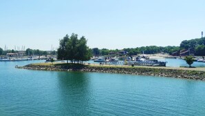 A marina with boats docked, a small island with trees, and a clear blue sky.