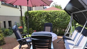 An outdoor patio with a table and chairs, a swing chair, and a large umbrella. - cozy functional apartment (Lauterbach)