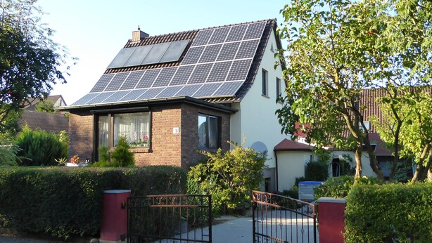 A house with solar panels on the roof, a gated entrance, and a well-maintained garden. - cozy functional apartment (Lauterbach)