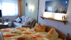 A bedroom with a large bed, a sofa, a small table with a vase, and a painting on the wall. - cozy functional apartment (Lauterbach)