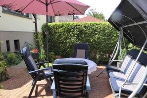 An outdoor patio with a table and chairs, a swing chair, and a large umbrella. - cozy functional apartment (Lauterbach)