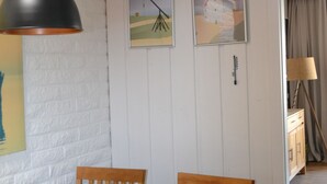 Ein Essbereich mit einem Holztisch, Stühlen, einer Pendelleuchte und zwei gerahmten Bildern an der Wand.