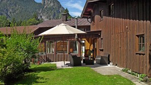 Ein Holzhaus mit Terrasse, großen Fenstern und Bergblick.
