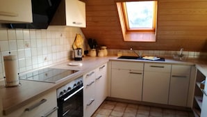 Ett kompakt kök med vita skåp, en inbyggd ugn, en diskho och ett fönster med utsikt.