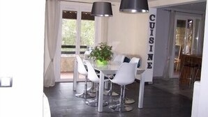 A dining area with a table and chairs, a potted plant, and a sign that reads "CUISINE".