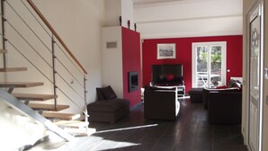 A living room with a staircase, a television, and a red accent wall.
