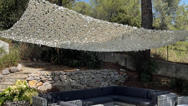 An outdoor seating area with a stone wall, wicker furniture, and a white umbrella.