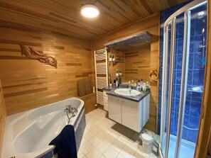 A modern bathroom with a wooden interior, a freestanding bathtub, a vanity with a sink and mirror, and a shower enclosure.