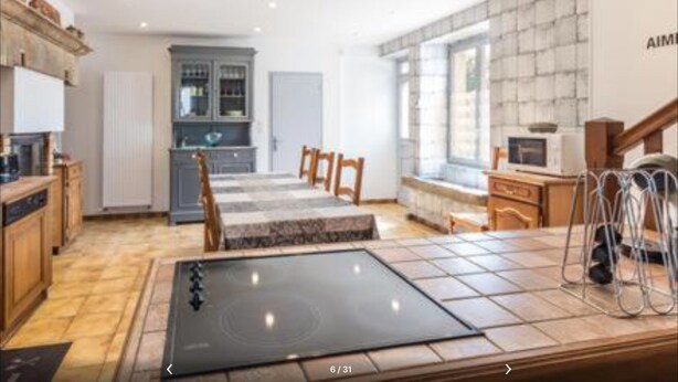 Una cocina moderna con armarios de madera, horno empotrado y un comedor con mesa y sillas.