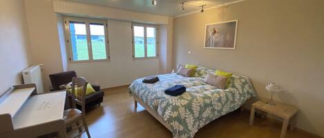 A bedroom with a bed, a desk, a chair, and a window.