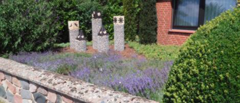 A stone wall with a garden featuring lavender and various shrubs.