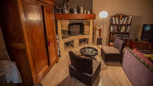 Ein gemütliches Wohnzimmer mit Kamin, Bücherregal und einer bequemen Sitzecke.