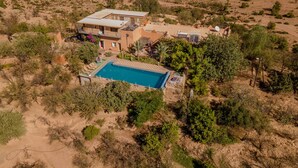 Ein Luftbild eines Anwesens in der Wüste mit Pool, mehreren Gebäuden und spärlicher Vegetation.