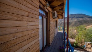 Eine Holzhütte mit einem Balkon mit Blick auf eine gebirgige Landschaft.