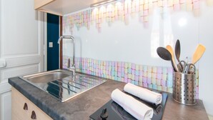 A kitchen with a stainless steel sink, a modern faucet, and a colorful backsplash.