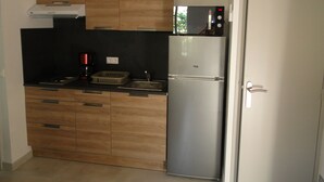 Uma cozinha compacta com armários de madeira, geladeira de aço inoxidável e cafeteira.