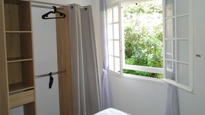 Quarto com guarda-roupa de madeira, cama e janela com cortinas.