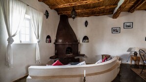A rustic interior with a stone fireplace, a wooden ceiling, and a curved bench. - Villa Tigmin Eden with traditional Moroccan decor. (Essaouira)