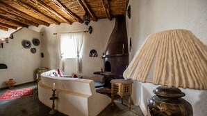 A rustic interior with a stone fireplace, a wooden ceiling, and a traditional lamp. - Villa Tigmin Eden with traditional Moroccan decor. (Essaouira)