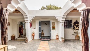 A traditional courtyard with a central rug, potted plants, and a wooden door. - Villa Tigmin Eden with traditional Moroccan decor. (Essaouira)