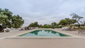 A rectangular pool with a surrounding deck, lounge chairs, and a small seating area with cushions. - Villa Tigmin Eden with traditional Moroccan decor. (Essaouira)