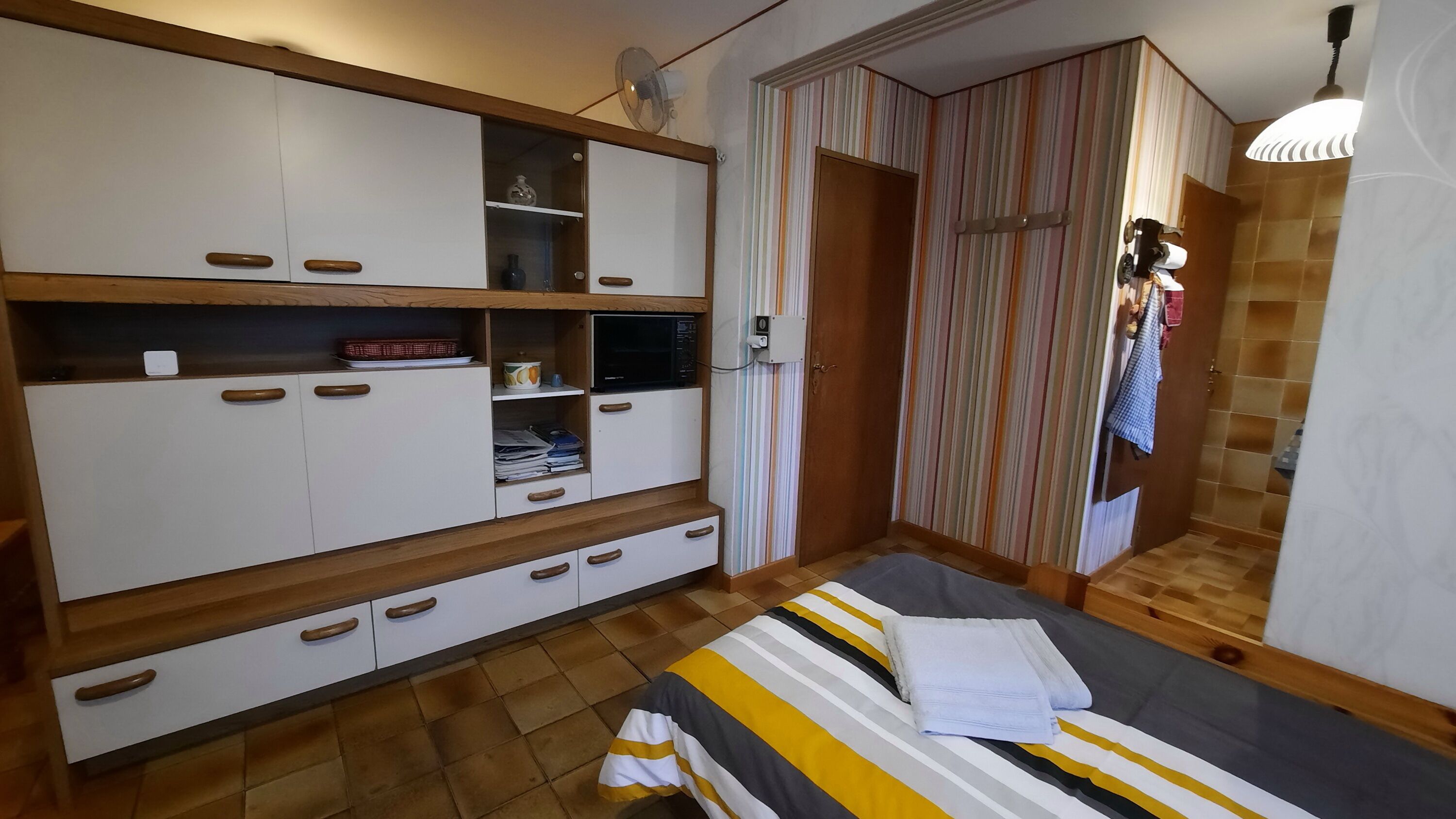 A bedroom with a bed, a wardrobe, and a mirror.