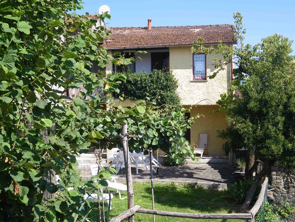 A rustic building with a tiled roof, a small garden with a wooden fence, and outdoor furniture.