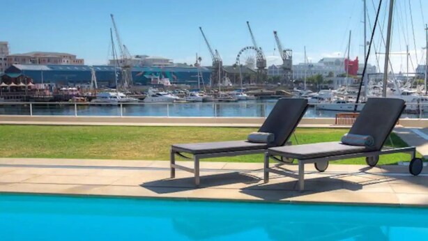 A swimming pool with two lounge chairs and a marina view in the background. - Quiet GF apartment at the water, V&A waterfront, overlooking Table Mountain, free WiFi (Cape Town)