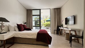 A modern hotel room with a large bed, a desk, a chair, a TV, and a view of the outdoors. - Quiet GF apartment at the water, V&A waterfront, overlooking Table Mountain, free WiFi (Cape Town)