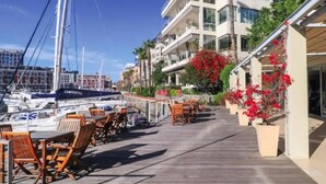 A waterfront patio with outdoor seating and a view of boats and buildings. - Quiet GF apartment at the water, V&A waterfront, overlooking Table Mountain, free WiFi (Cape Town)