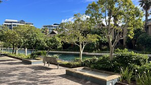 A landscaped outdoor area with a water feature, benches, and a variety of trees. - Quiet GF apartment at the water, V&A waterfront, overlooking Table Mountain, free WiFi (Cape Town)