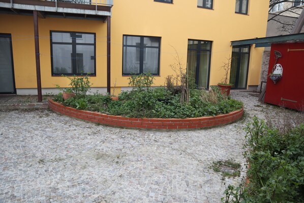 Ein Innenhof mit Kopfsteinpflasterboden, umgeben von einem Ziegelpflanzkübel mit verschiedenen Pflanzen.
