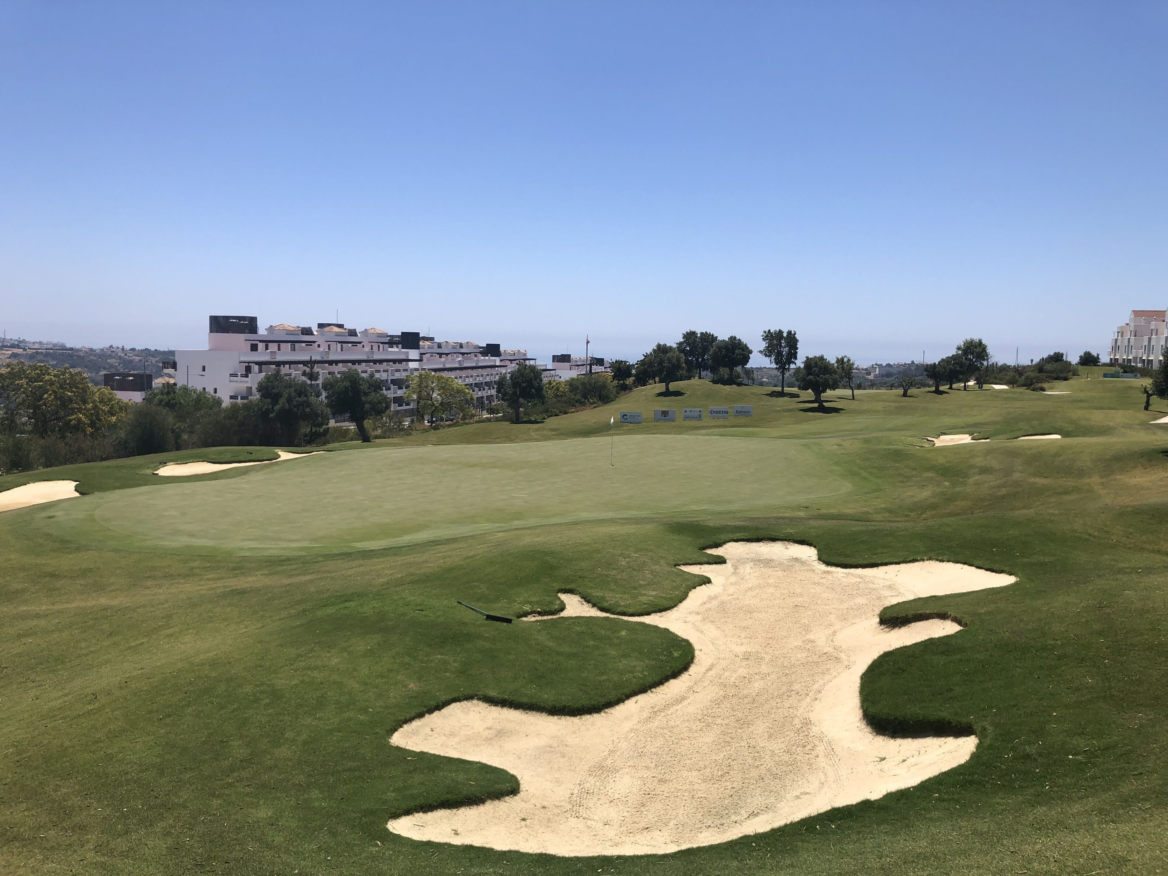 Un campo da golf con bunker, una bandiera e un cielo sereno.