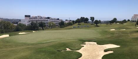 Un campo da golf con bunker, una bandiera e un cielo sereno.