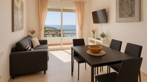 Un salon moderne avec un canapé, une table à manger, des chaises, un téléviseur et une vue sur la mer.